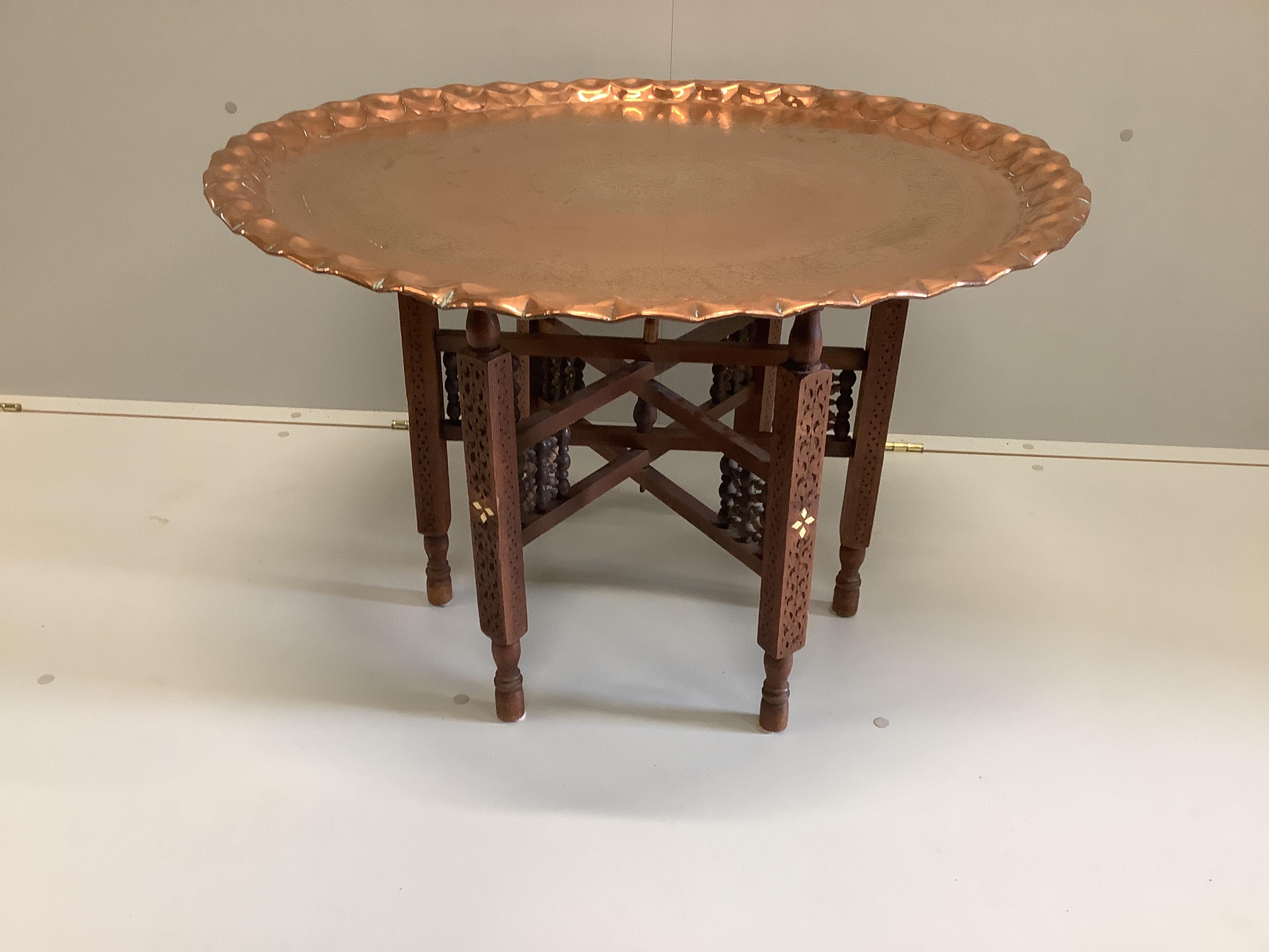 A Moorish circular copper tray top occasional table on folding stand, diameter 77cm, height 53cm